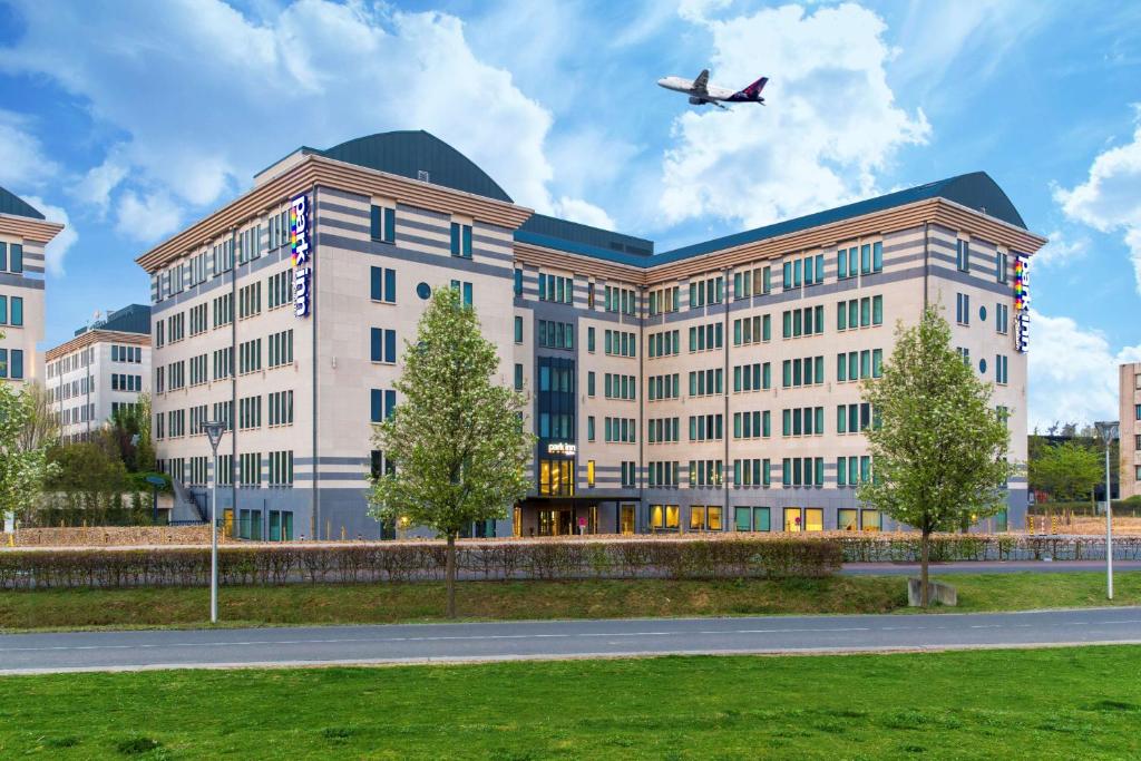 迭戈姆布鲁塞尔机场丽柏酒店的一座大型建筑,飞机飞过它