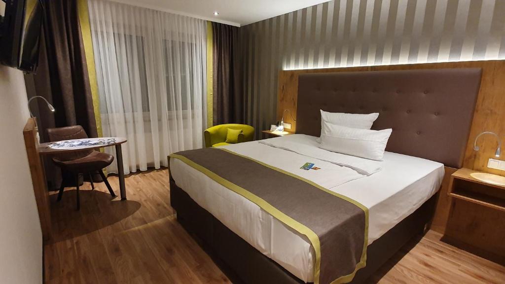 迪尔门AKZENT Hotel Merfelder Hof的酒店客房设有一张大床和一张桌子。