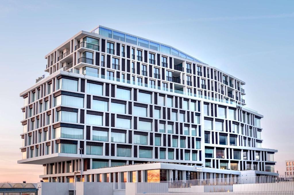 布鲁日Radisson Blu Hotel, Bruges的一座高大的办公室建筑,设有玻璃窗