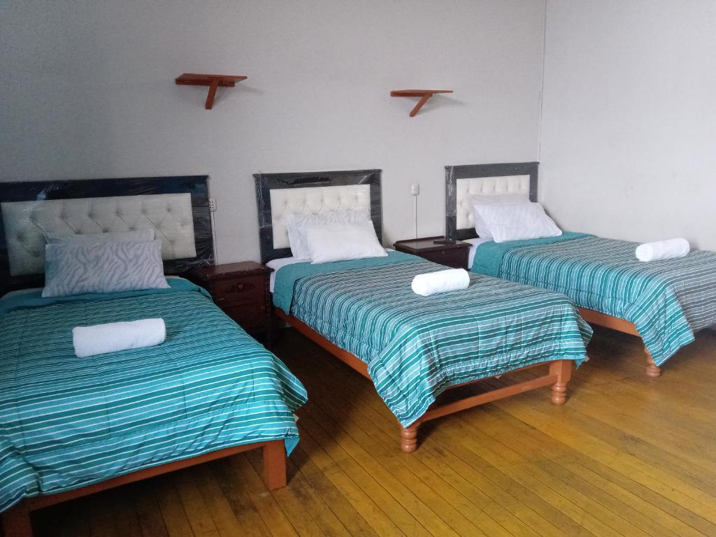 阿雷基帕Misti Hostel B&B的一间设有三张床的客房,配有床单