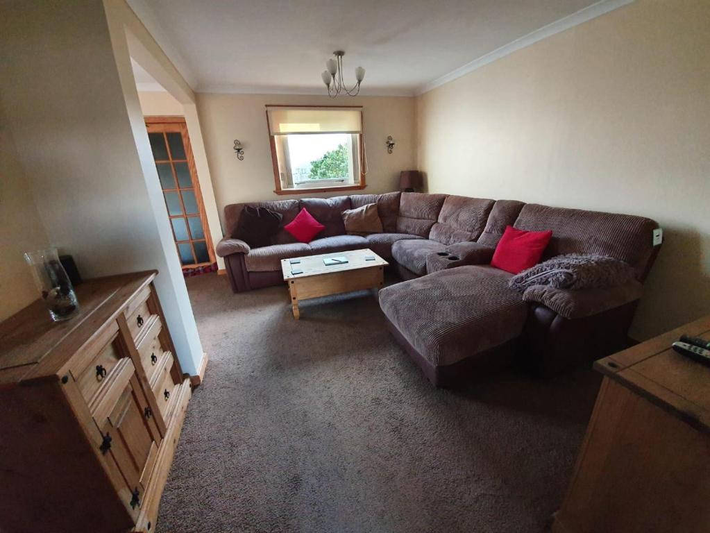 巴里瓦尼奇Taigh nam Piobaireach的客厅配有棕色沙发和红色枕头