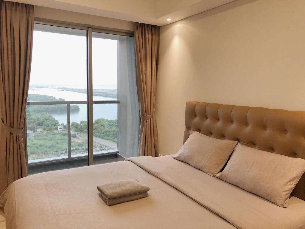 雅加达Gold Coast PIK Sea View Apartments by LongeSuites的一间卧室设有一张大床和大窗户