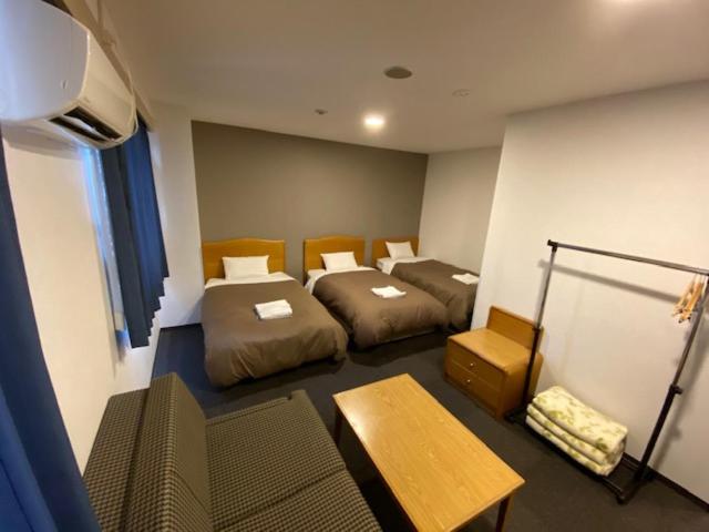泉佐野新裕酒店的一间设有两张床和一张桌子的房间