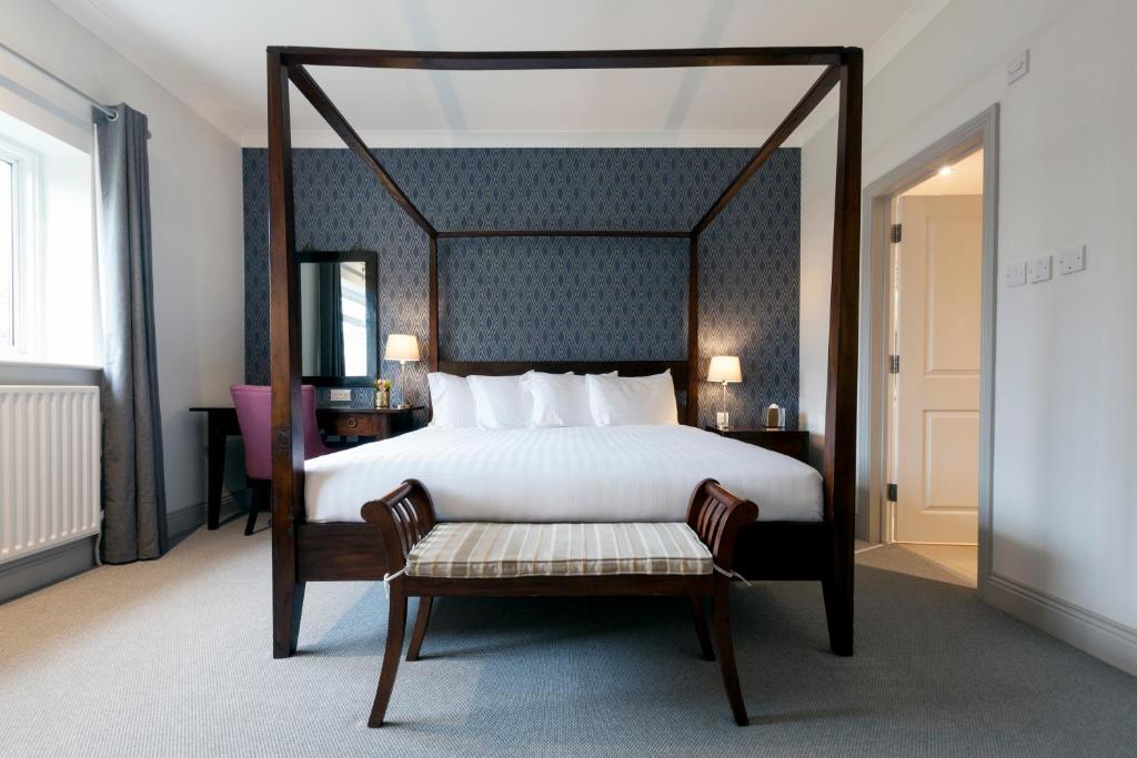 吉尔福德阿斯佩里昂山坡酒店的一间卧室配有一张带长椅的天蓬床。
