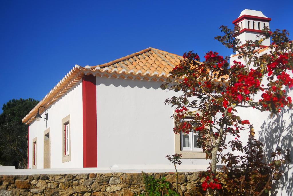 马夫拉Casas da Tia Alice的白色的房子,有红色的屋顶,一棵树上花红