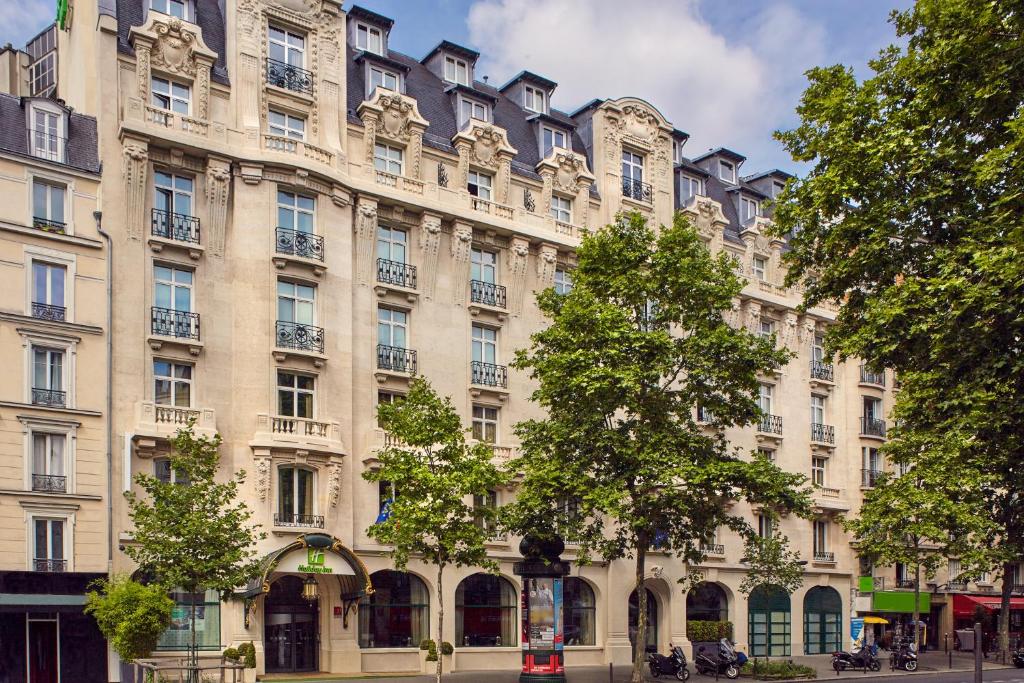 巴黎Holiday Inn Paris - Gare de Lyon Bastille, an IHG Hotel的前面有树木的大棕褐色建筑