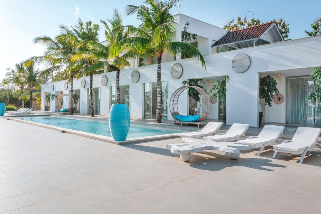 乌鲁瓦图Terrazza Plenilunio的一个带游泳池、白色椅子和棕榈树的度假村