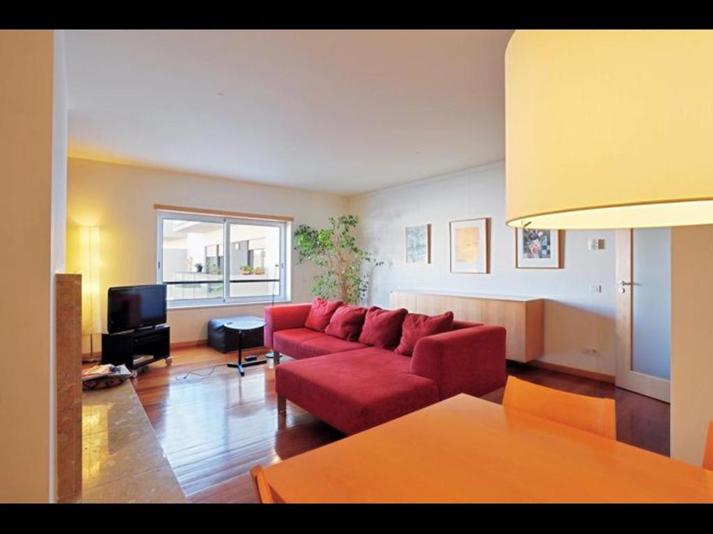里斯本世博会舒适当代旅馆的客厅配有红色沙发和电视