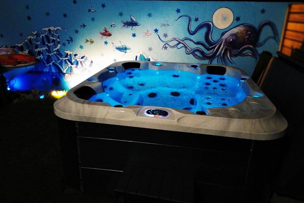 坎佩尔LOGEMENT ATYPIQUE BIEN ETRE AU CŒUR DE LA NATURE的浴室设有蓝色浴缸和章鱼墙