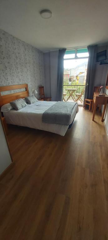 坎加斯-德奥尼斯阿吉拉里尔酒店的一间卧室配有一张床,铺有木地板