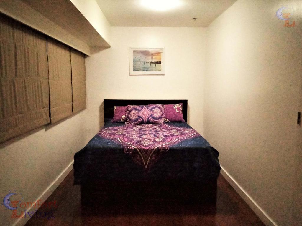 马尼拉BGC Fort Victoria的一间卧室配有一张床铺,床上铺有紫色毯子