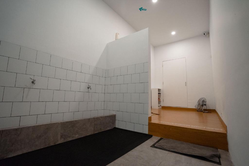 雅加达Bobopod Kota Tua, Jakarta的一间空浴室,设有白色瓷砖墙壁和长凳