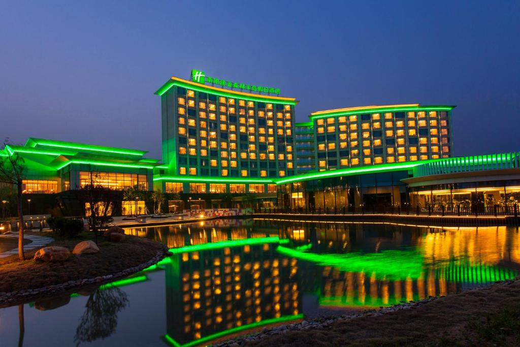 南阳Holiday Inn Nanyang, an IHG Hotel的水体前有绿灯的建筑