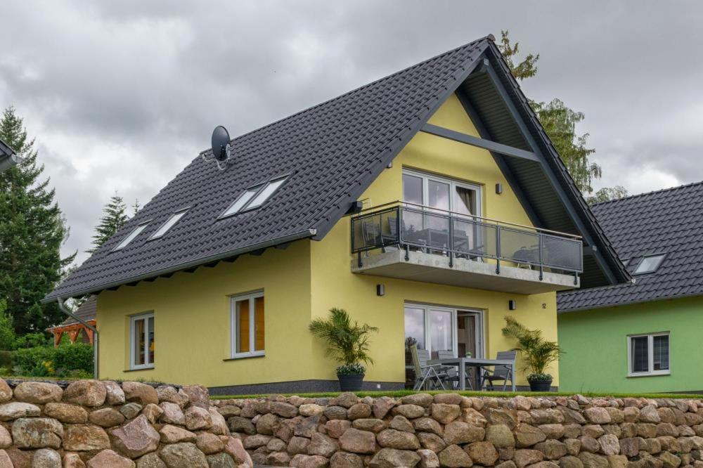 马林费尔德U12 EG - Charmante Ferienwohnung am See mit Kamin in Röbel an der Müritz的黄色和绿色的房子,有黑色屋顶