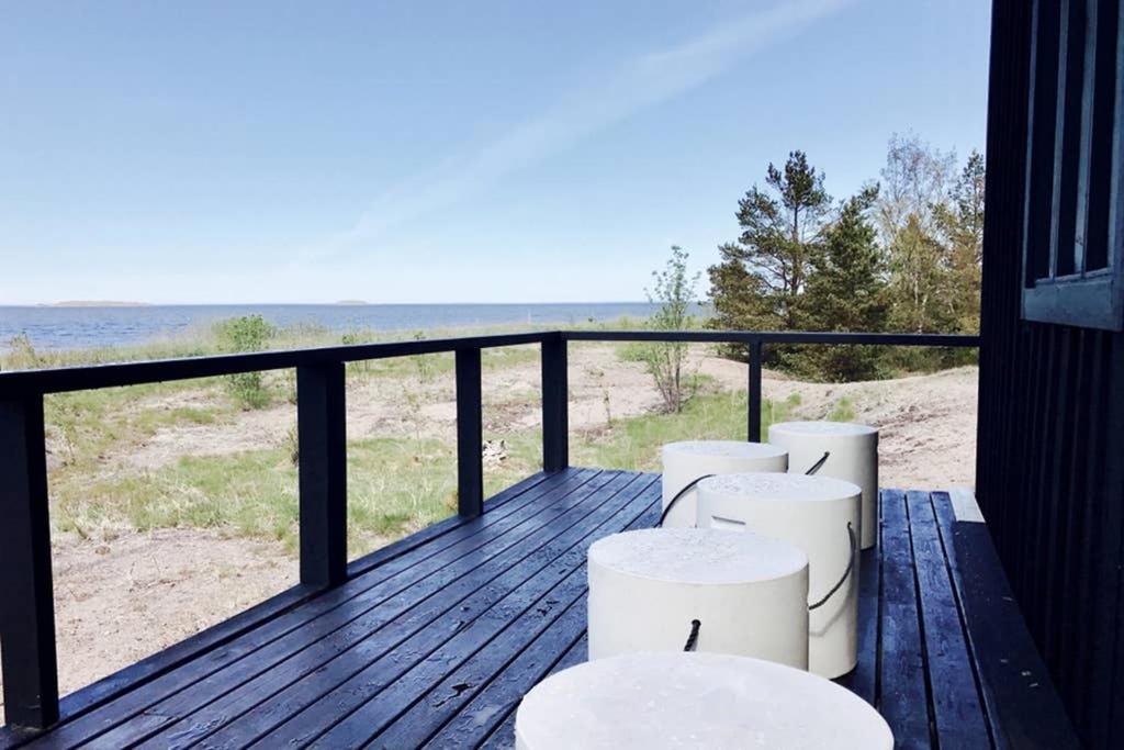科科拉H A R R B Å D A - kaksi mökkiä merenrannalla的阳台设有4张白色凳子,享有海滩美景。