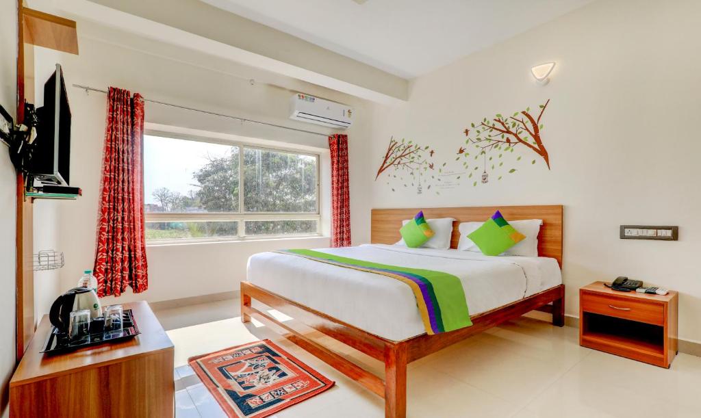 库斯哈尔纳加尔Treebo Trend Atithi Comforts 1 Km From Nisargadhama Forest的一间卧室设有一张床、一台电视和一个窗口。