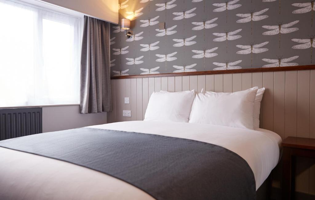 纽尼顿Chase Inn By Greene King Inns的一间卧室配有一张白色大床和蝴蝶壁纸