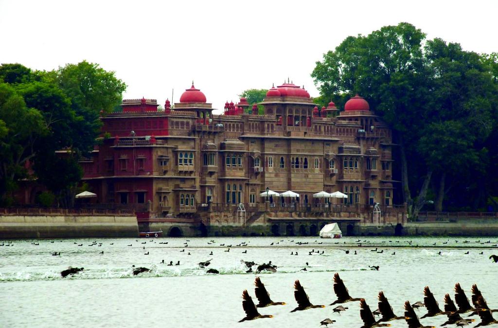 GajnerGajner Palace-Heritage by HRH Group of Hotels的一座大型建筑,前面的水面上的人