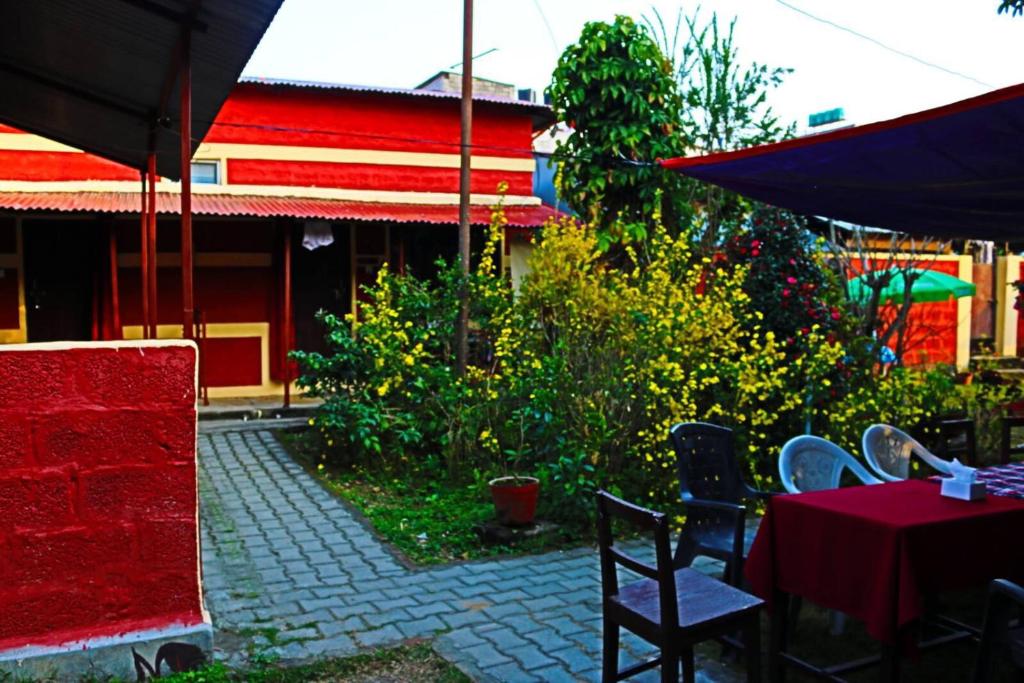 博卡拉Gurkha Lodge的庭院配有桌椅和遮阳伞。