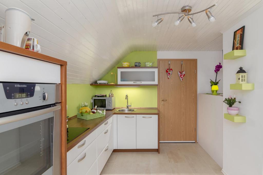 博希尼Apartments Sara的一间小厨房,配有白色的橱柜和绿色的墙壁