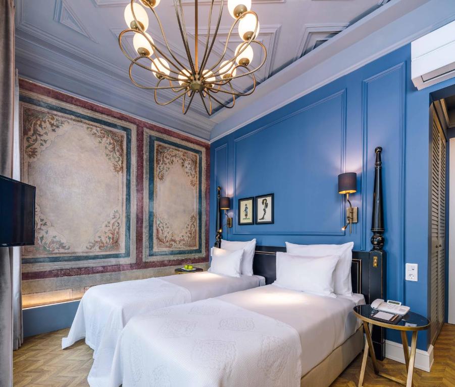 伊斯坦布尔The Soul Istanbul Hotel的配有蓝色墙壁和吊灯的客房内的两张床