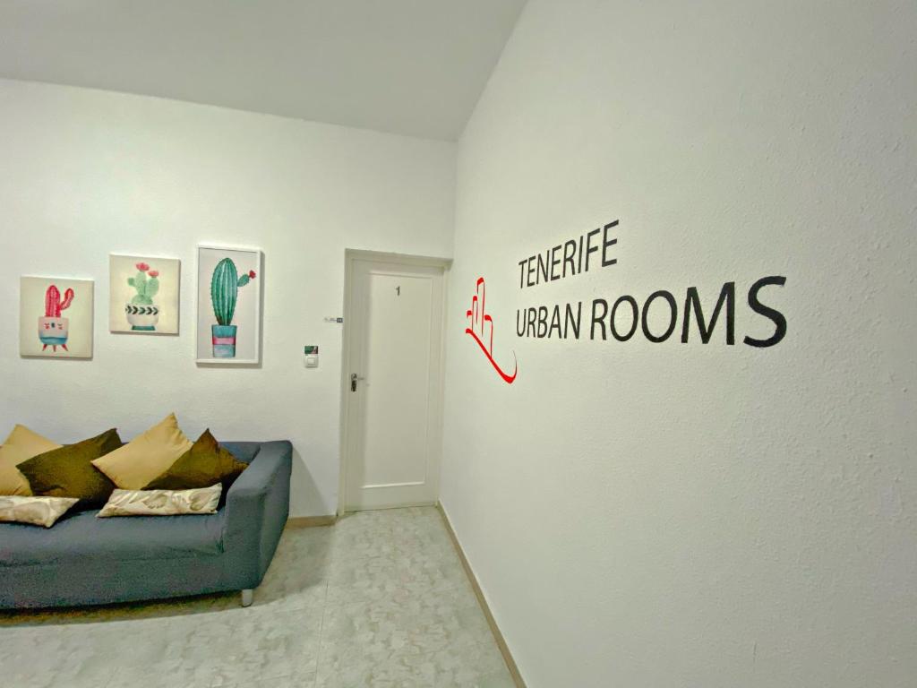 圣克鲁斯-德特内里费TENERIFE URBAN ROOMS的客厅配有沙发和墙上的标志