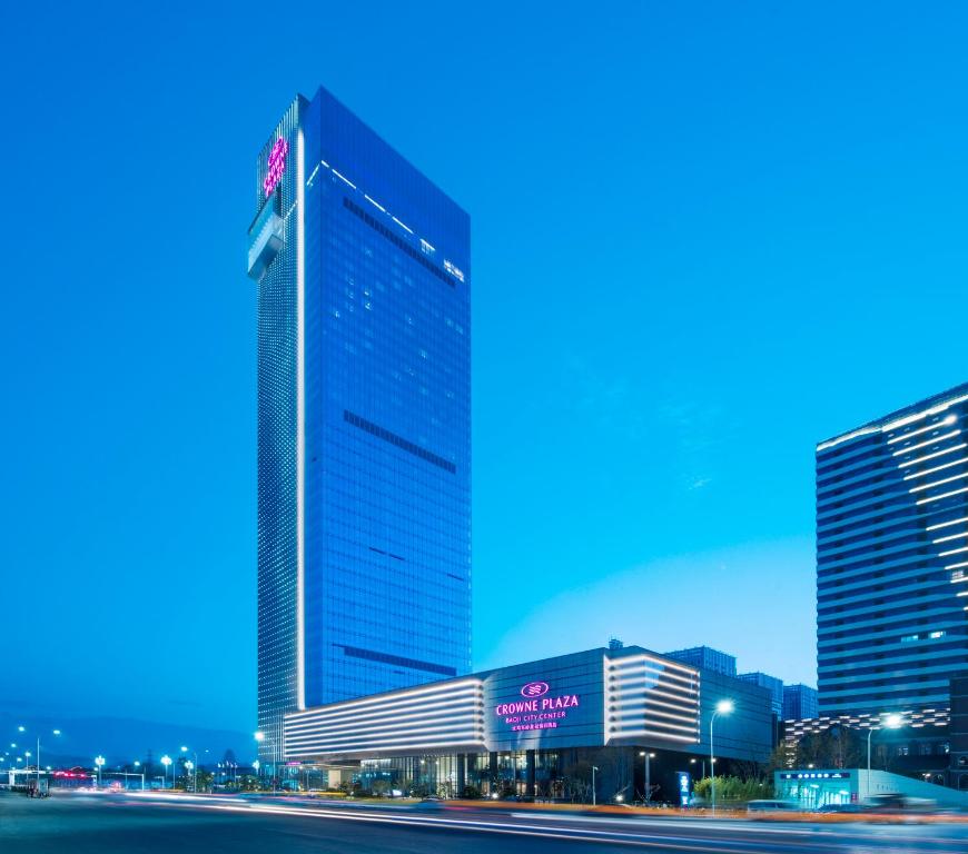 宝鸡宝鸡东岭皇冠假日酒店的一座高大的建筑,旁边有一个标志