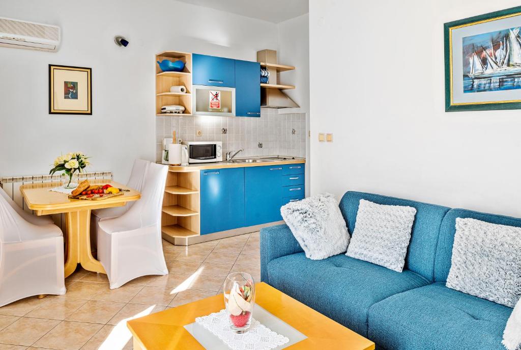 希贝尼克Apartmani Barun的一间带蓝色沙发的客厅和一间厨房