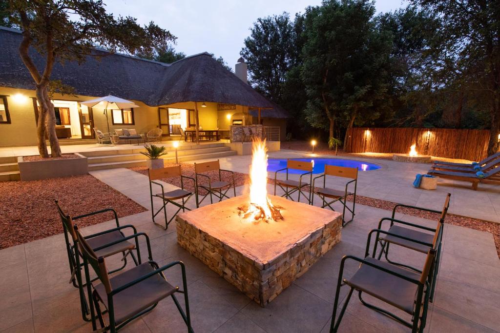 帕拉博鲁瓦Kingly Bush Villa的一个带火坑和椅子的庭院以及一个游泳池