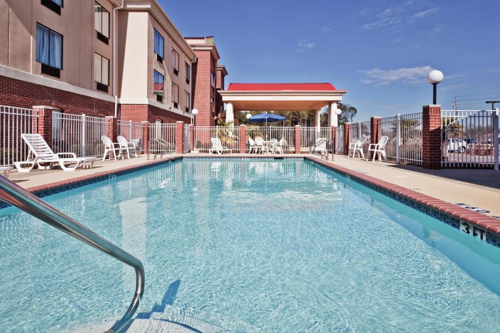 佛瑞斯特森林智选假日套房酒店的一座带椅子的游泳池以及一座建筑