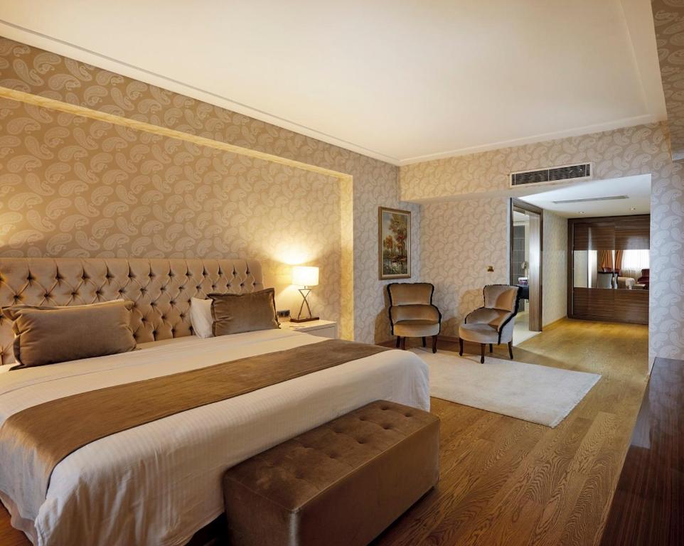 科尼亚Anemon Grand Konya Otel的一间大卧室,配有一张大床和椅子