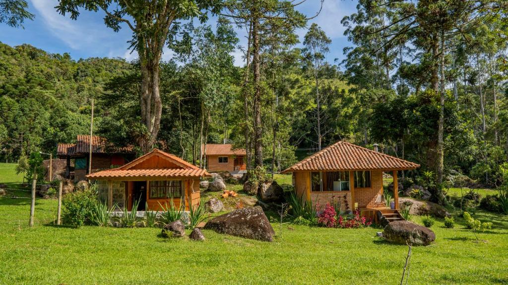 维奥康德马奥Chalés Das Estrelas的两栋小别墅,位于一个树木繁茂的田野