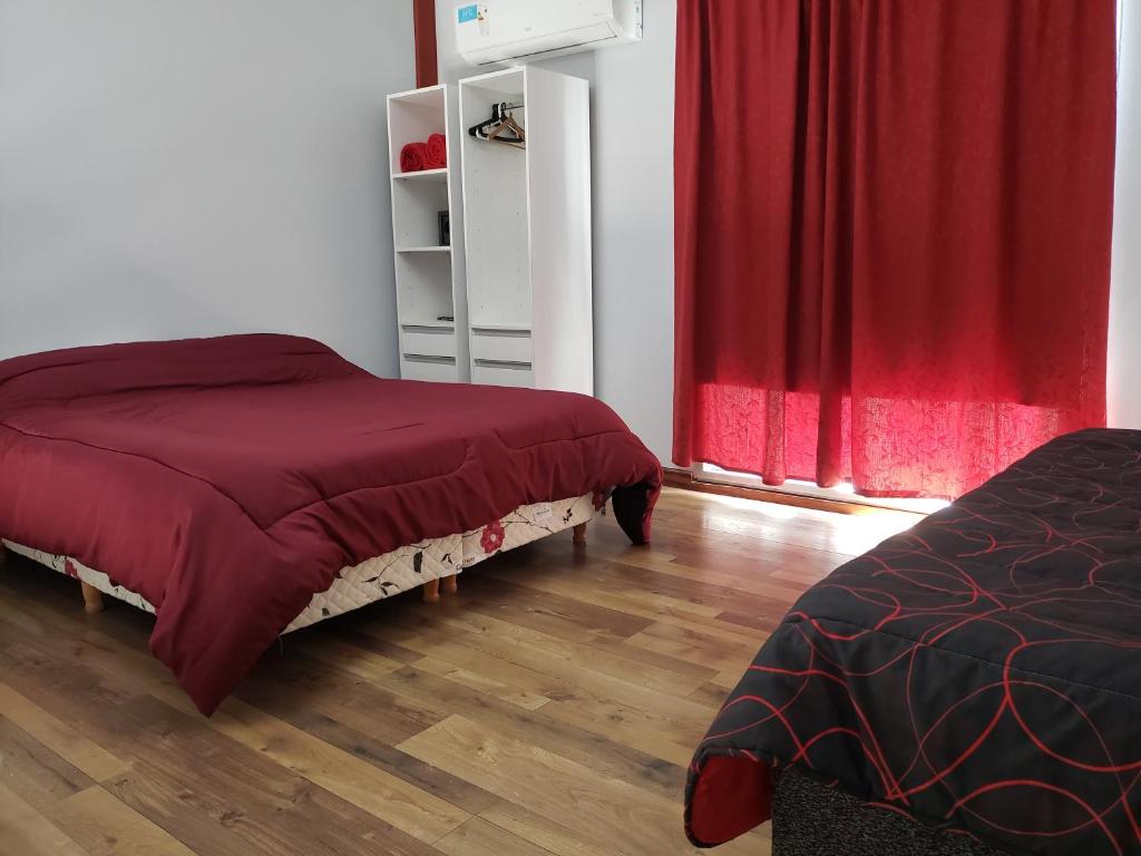 埃塞萨Lugones的一间卧室设有两张床和红色窗帘