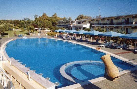阿尔库季岛Lintzi Hotel的度假村内的大型游泳池,配有蓝色遮阳伞