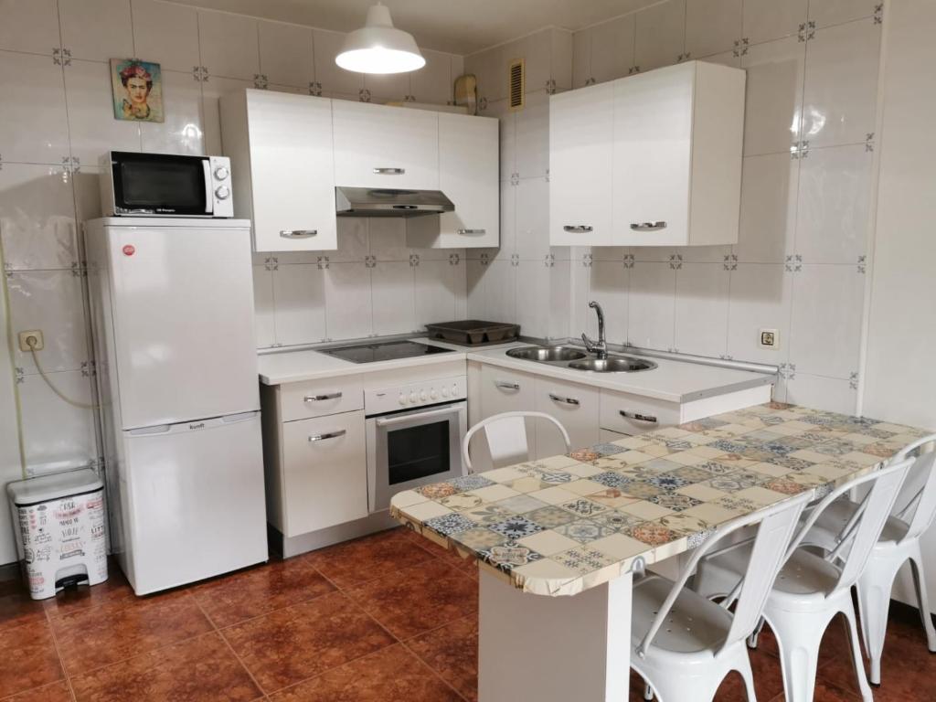 马林Casa Álvaro的一间厨房,配有白色家电和桌椅