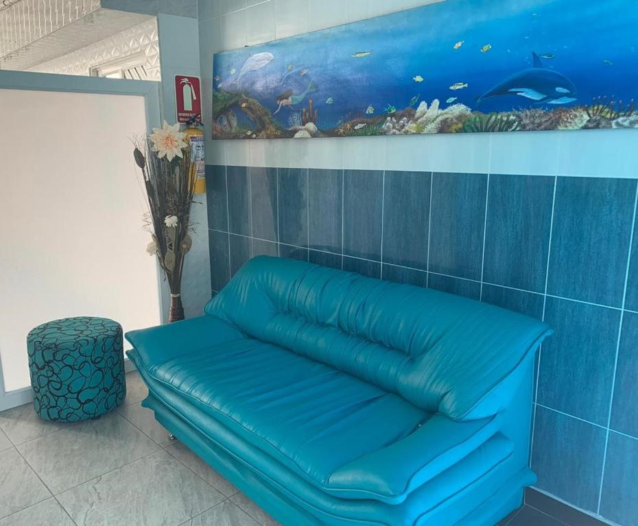 圣安德烈斯Posada Cocos Place的一张蓝色的沙发,位于一间有鱼画的房间