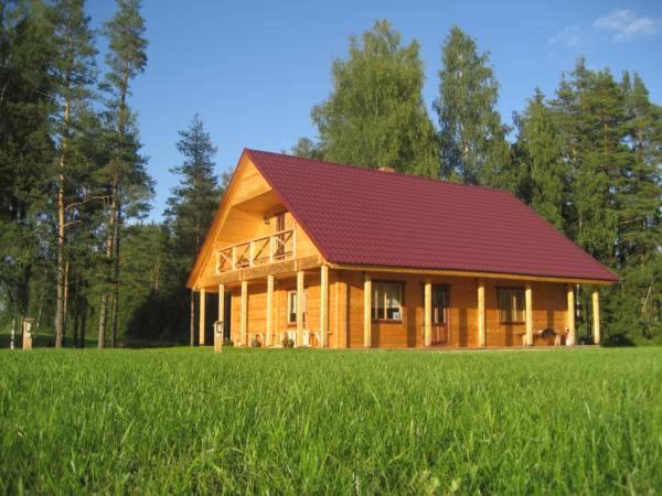 VaidavaMeldri的一座大型木房子,在田野上设有红色屋顶