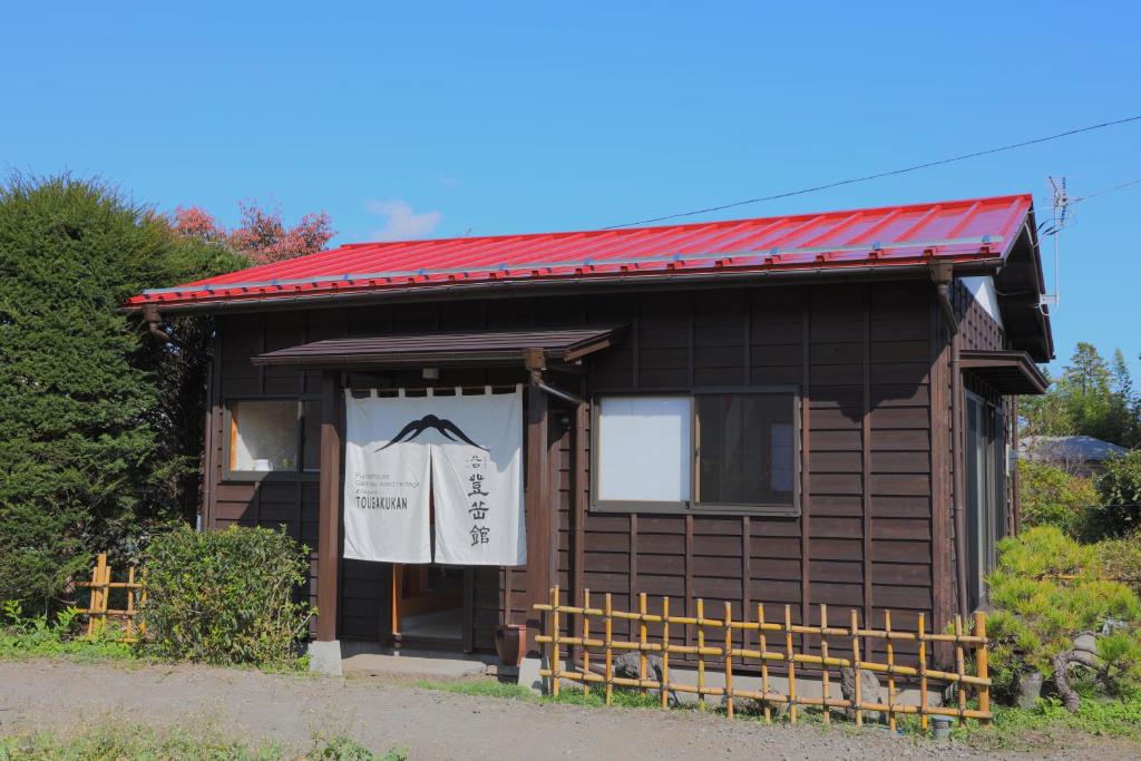 富士吉田市Kitaguchi Tougakukan的一间红色屋顶的小房子,上面有标志