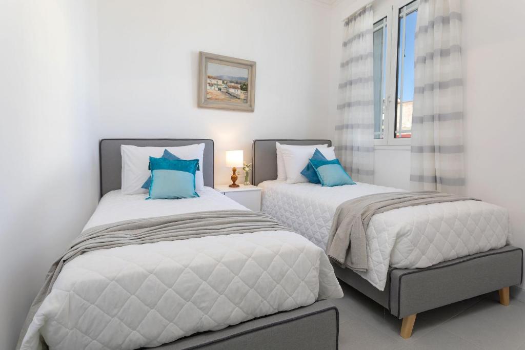 扎金索斯镇Andriani Apartment的白色客房的两张床,配有蓝色枕头