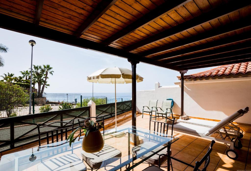 阿德耶El Beril Ocean Front的阳台设有游泳池、桌子和椅子。