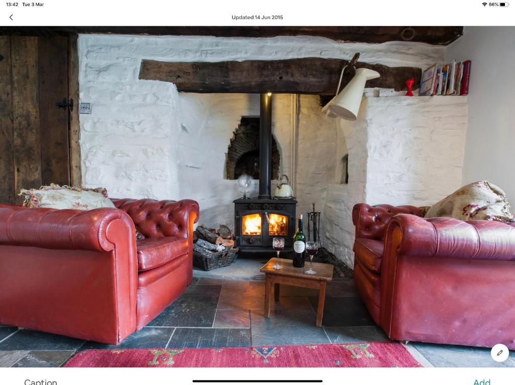 TalybontTy Fferm Hen, The Ancient Farmhouse的客厅配有2张红色皮革沙发和壁炉