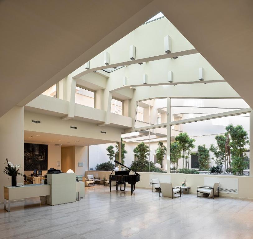 博洛尼亚伯洛格纳珀缇西酒店的一个大大堂,配有三角钢琴和椅子