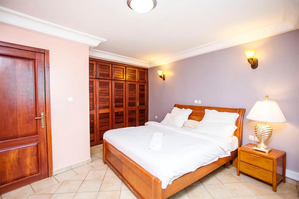 杜阿拉Residence Le Carat的一间卧室配有一张带白色床单和一盏灯的床。