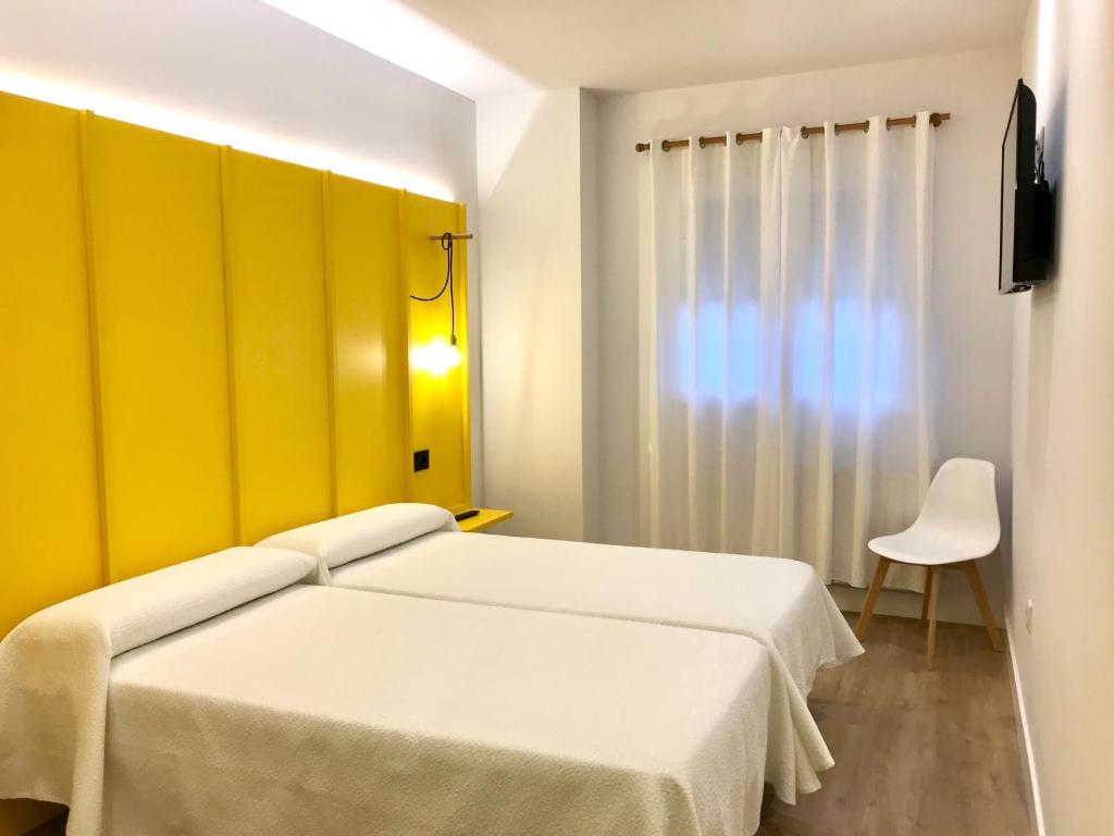 欧德鲁佐Albergue O Burgo的一间卧室设有两张床和黄色的墙壁