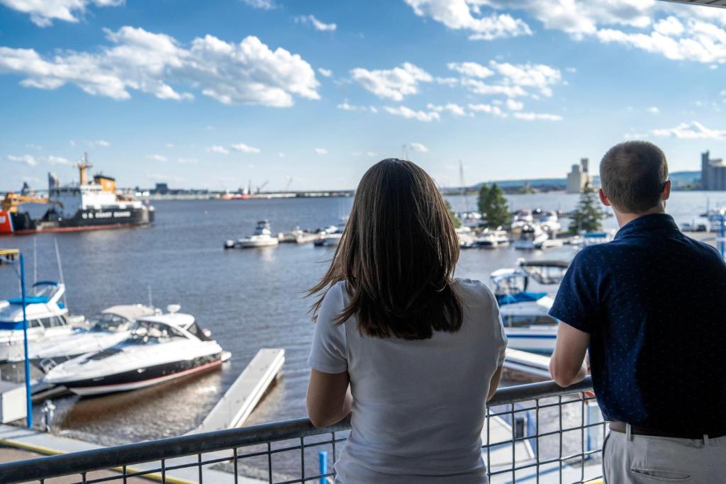 德卢斯公园岬码头酒店的男人和女人站在一个俯瞰船只的阳台