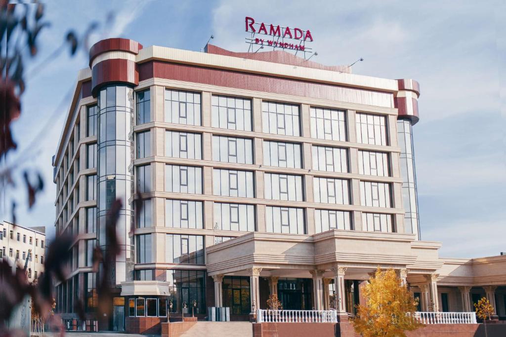 奇姆肯特Ramada by Wyndham Shymkent的一座高大的建筑,上面有标志