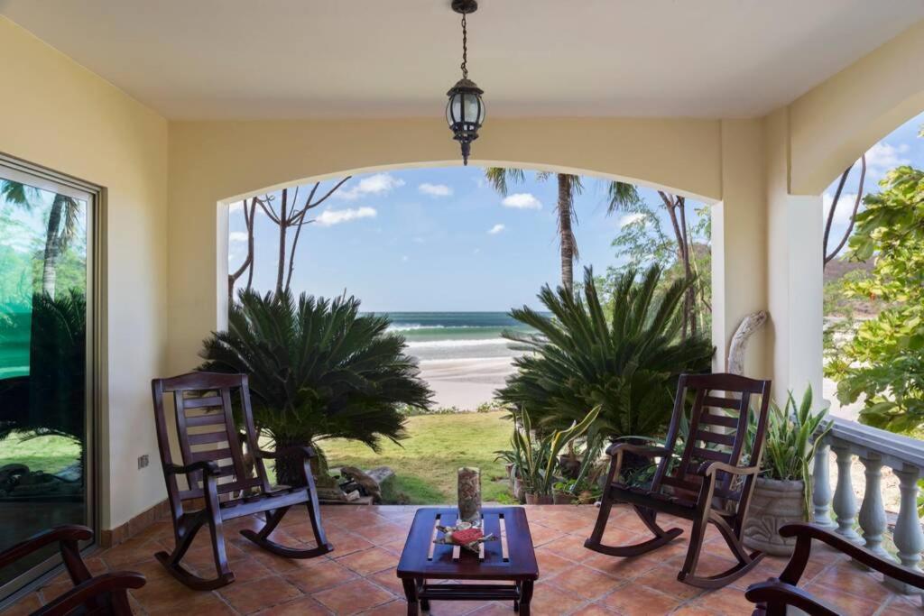 里瓦斯Villas Iguana A-2 Beachfront Condo的一个带椅子和桌子的门廊,享有海滩美景