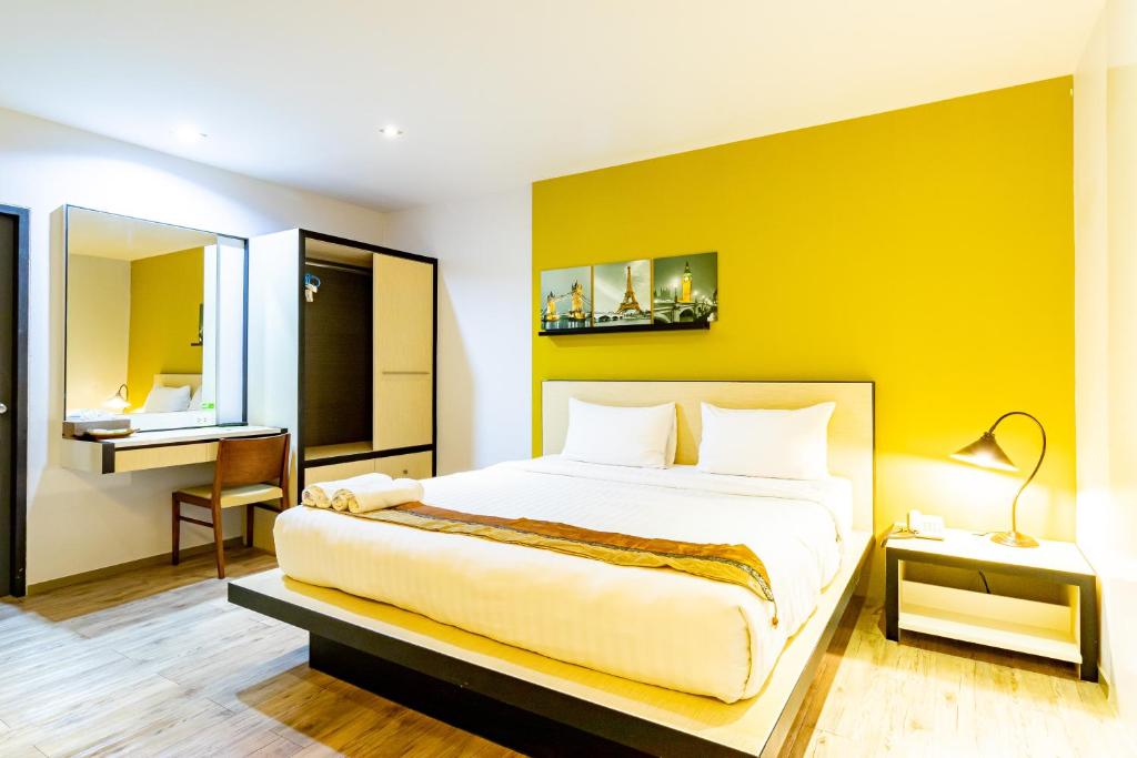 合艾Thongmanee Hotel的一间卧室设有一张黄色墙壁的大床