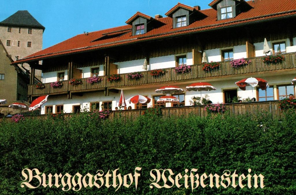 雷根Burggasthof Weißenstein的前面有雨伞的大建筑