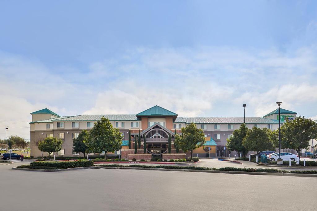 埃尔克格罗夫HOLIDAY INN EXPRESS & SUITES ELK GROVE CENTRAL - HWY 99, an IHG Hotel的一座大型建筑,前面设有停车场